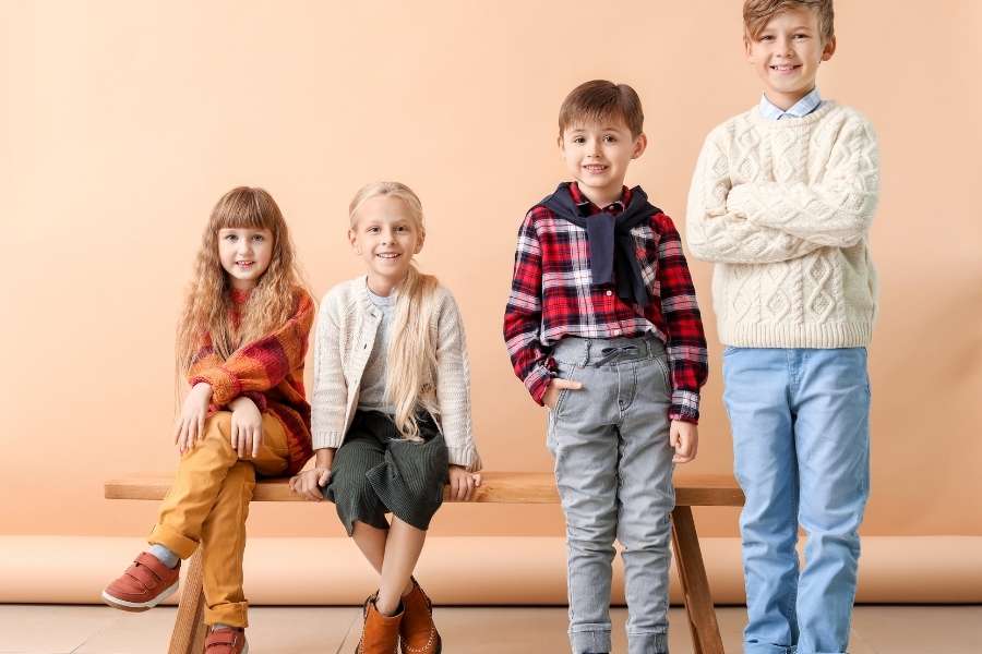 Groupe d'enfants souriants posant avec élégance pour une séance photo de mode enfantine.